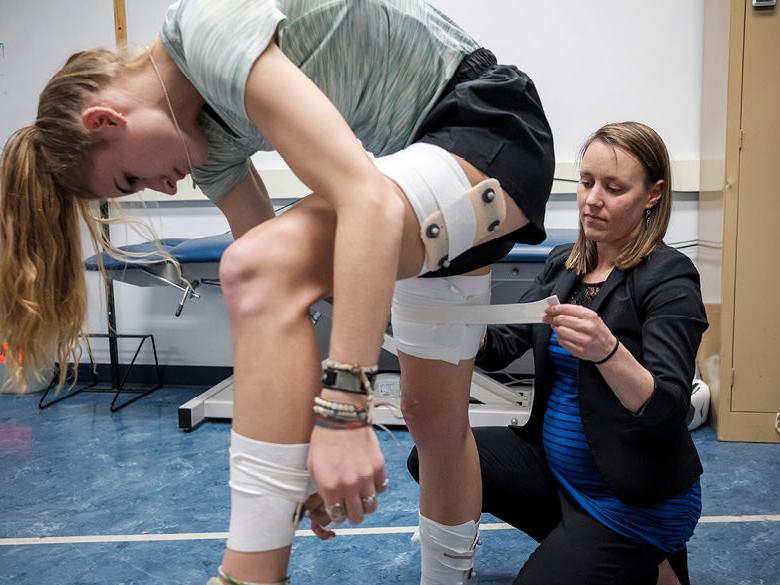 Student affixes monitoring equipment to other students' hamstrings and calf muscles in Human Movement Research Center
